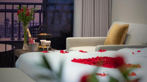 a living room with a table with red flowers on it at Grand Millennium Gizan in Jazan