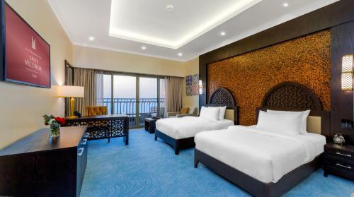 a hotel room with two beds and a television at Grand Millennium Gizan in Jazan