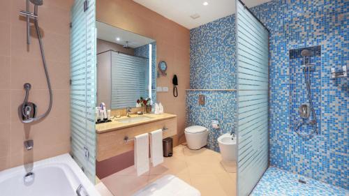 a bathroom with a tub and a sink and a shower at Grand Millennium Gizan in Jazan
