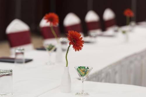 a red flower in a vase on a table at The Fern Residency Galaxy Mall in Āsansol