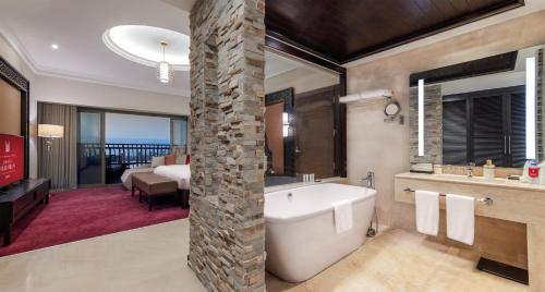 a bathroom with a bath tub and a bedroom at Grand Millennium Gizan in Jazan