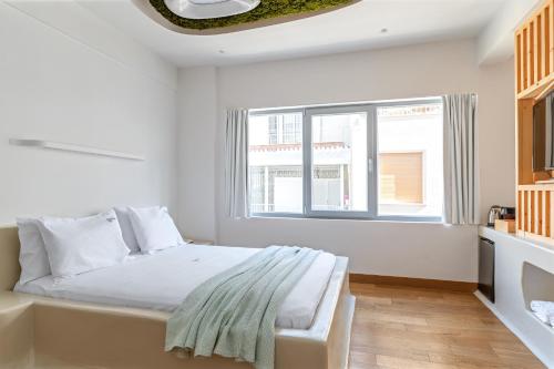 a white bedroom with a bed and a window at LOFUS Bio-Suites in Athens