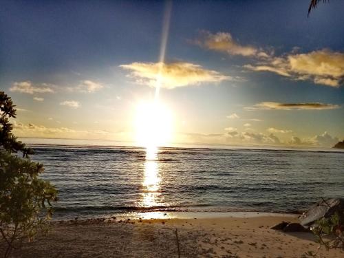a sunset on the beach with the sun setting at Roz A Mer - Beach Apartment in Mahe