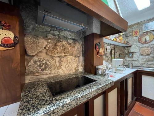 a kitchen with a stone wall and a sink at Casa do Alto (ground floor apartment) in Adaúfe