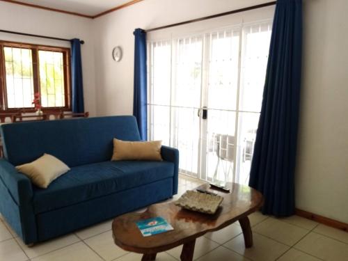 a living room with a blue couch and a coffee table at Roz A Mer - Beach Apartment in Mahe