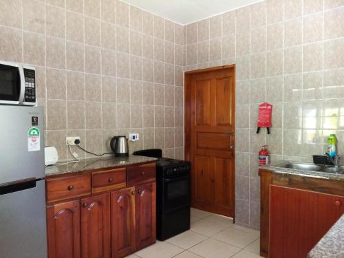 a kitchen with a refrigerator and a sink and a stove at Roz A Mer - Beach Apartment in Mahe