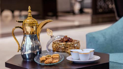 a table with a tea kettle and cups of pastries at Grand Millennium Gizan in Jazan