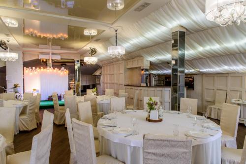 una sala de banquetes con mesas y sillas blancas y lámparas de araña en Knyazhyi Dvir en Sokilnyky