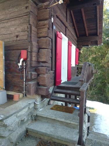 a porch of a log cabin with red doors at Petit chalet rustique et bucolique in Bovernier