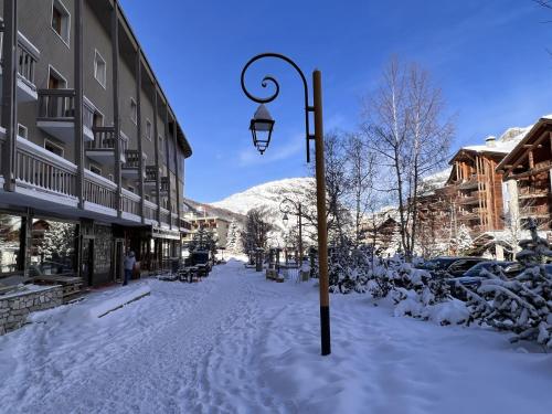 una calle cubierta de nieve con un poste de luz en Everest Hotel, en Val dʼIsère