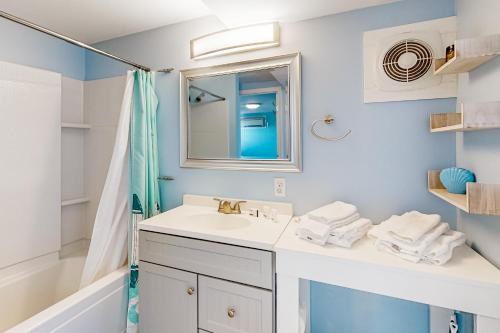 La salle de bains est pourvue d'un lavabo, d'un miroir et d'une baignoire. dans l'établissement First Street Retreat Lower, à Mexico Beach