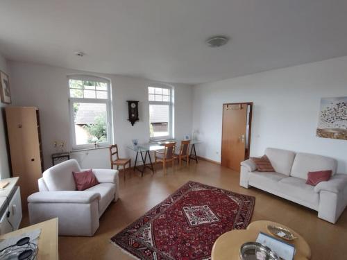 una sala de estar con 2 sofás blancos y una mesa. en Schöne Wohnung, direkt an der Weser, mit Kaminofen, en Hessisch Oldendorf