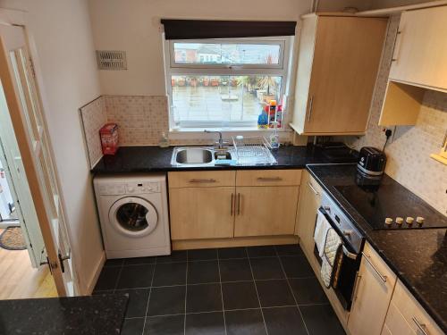 a kitchen with a sink and a washing machine at No 11 3 BED SERVICED APPARTMENT TOWN CENTRE in Girvan