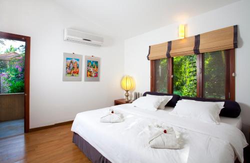 a bedroom with two beds with white sheets and windows at Shreyas Retreat in Nelamangala