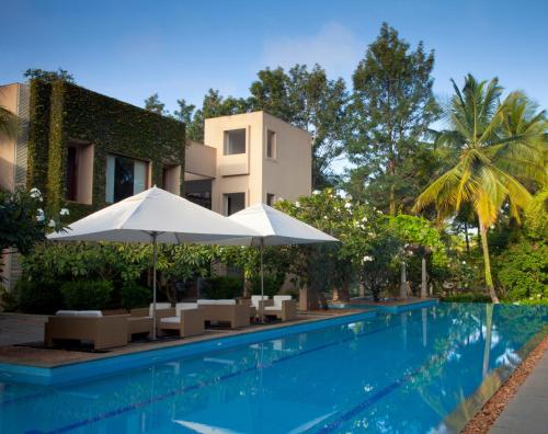 a swimming pool with umbrellas and chairs next to a building at Shreyas Retreat in Nelamangala