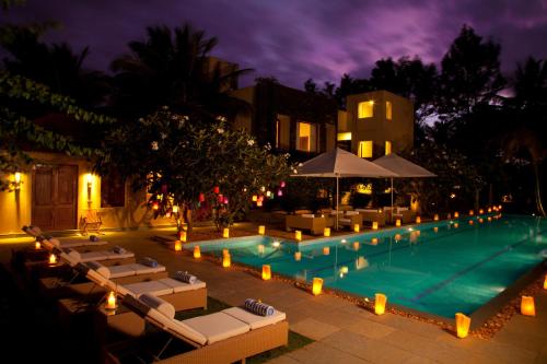 a swimming pool with lounge chairs and umbrellas at night at Shreyas Retreat in Nelamangala