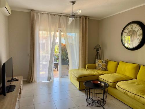 a living room with a yellow couch and a clock at Juangy’s Apartments in Las Adelfas Golf del Sur in San Miguel de Abona