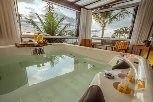 a bath tub with a view of the ocean at Hotel VillaReal Guaratuba - Caieiras in Guaratuba