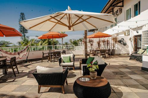 a patio with tables and chairs and an umbrella at Hotel VillaReal Guaratuba - Caieiras in Guaratuba