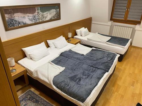 two beds in a room with two tables at Aparthotel Vučko - Apartman Olimpia in Jahorina