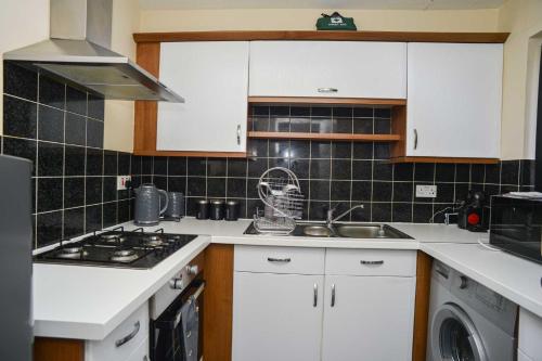 a kitchen with white cabinets and a sink and a stove at London's Calling U! A Lovely 2 BedHome Sleeps 1-5! in London