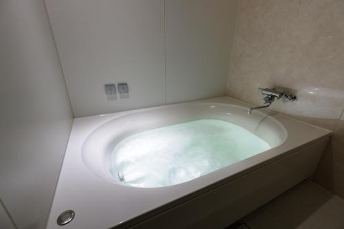 旭川ホテル818-大人専用 في اساهيكاو: حوض استحمام أبيض مع صنبور في الحمام