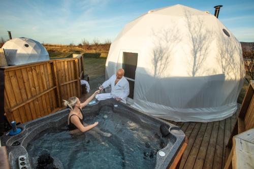 a man and a woman sitting in a hot tub next to a tent at Reykjavik Domes in Reykjavík