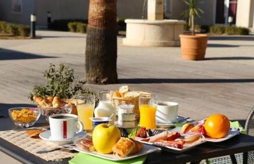 una mesa con comida para el desayuno y bebidas en ella en Hôtel Jasses de Camargue, en Gallargues-le-Montueux