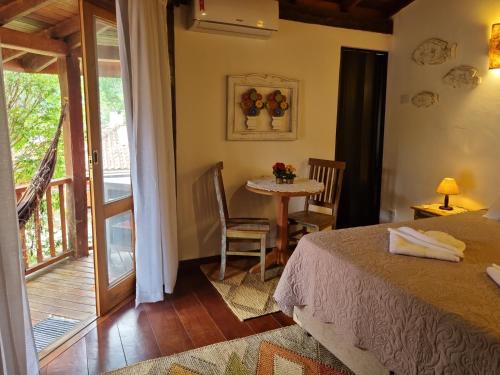 Habitación con cama, mesa y balcón. en Chalé dos Sonhos, en Ilhabela