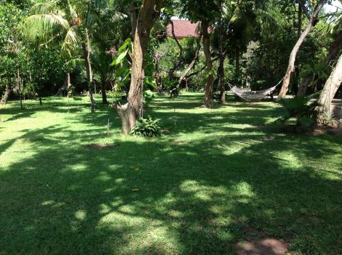 a green yard with trees and a hammock in the grass at Matahari Bungalow in Legian
