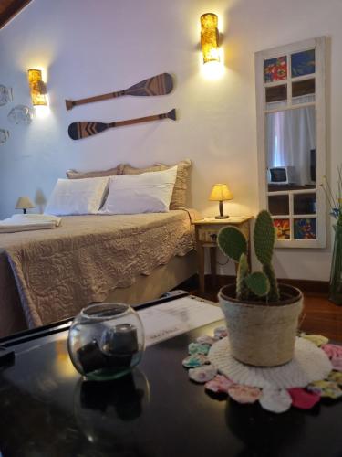 1 dormitorio con 1 cama y 1 mesa con cactus en Chalé dos Sonhos, en Ilhabela