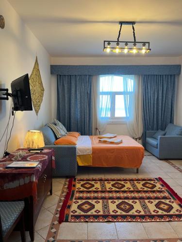 a bedroom with a bed and a couch and a tv at Deep Ashri in Marsa Alam City
