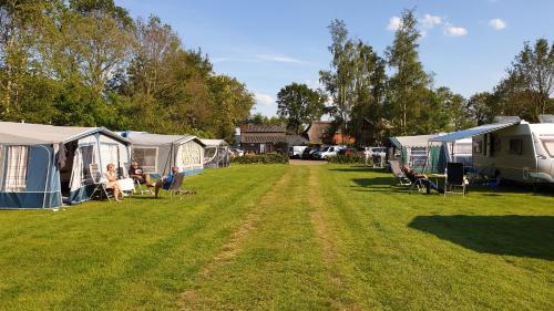 un groupe de terrains de camping avec des tentes et des personnes assises sur des chaises dans l'établissement Safaritent de Berghoeve, à Ruinen