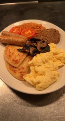 a plate of breakfast food with eggs sausage and mushrooms at The Caledonian in Portree
