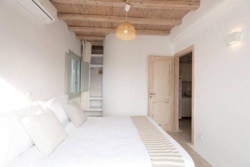 a white bedroom with a large bed with white pillows at Koumi Homes Mykonos in Elia