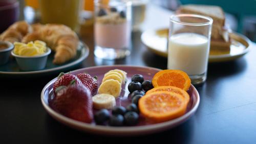a plate of fruit on a table with a glass of milk at ibis Styles Antofagasta in Antofagasta