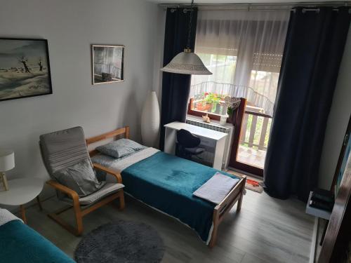 a bedroom with a bed and a chair and a window at Kikinda peace oaza in Kikinda