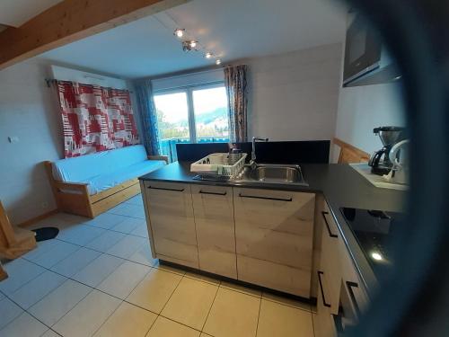 a kitchen with a sink and a couch in a room at Les Adrets in Gérardmer