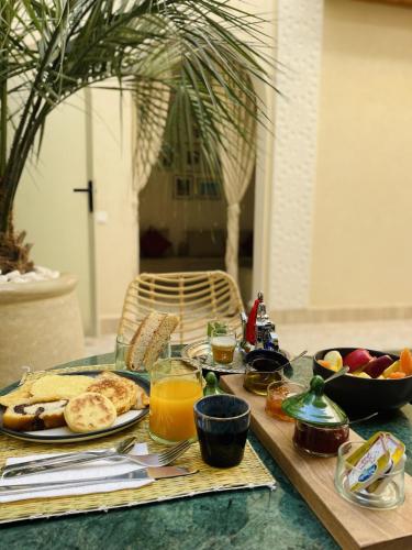 una mesa cubierta con productos para el desayuno y zumo de naranja en RIAD DAR BAYANE, en Marrakech