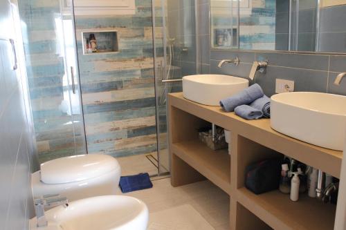 a bathroom with two sinks and a shower and a toilet at Case al mare di Cala Saccaia in Pittulongu