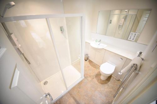 a white bathroom with a shower and a toilet at The Caledonian in Portree