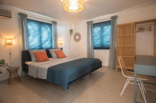 1 dormitorio con 1 cama con sábanas azules y almohadas de color naranja en NEW ! Cozy Casa en Oranjestad