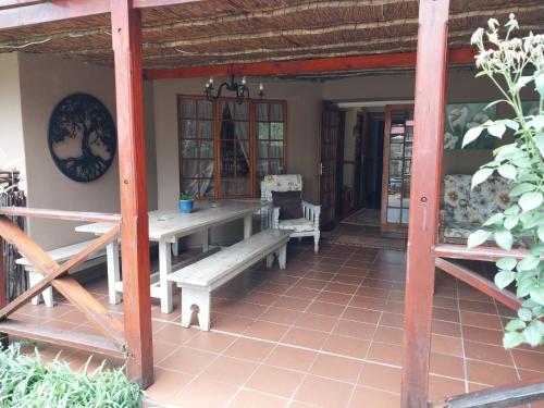 a porch of a house with a table and benches at Lily Guesthouse in Bloemfontein