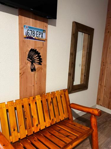 a wooden bench in a room with a sign on the wall at Hotel Le Ranch in Brûlon