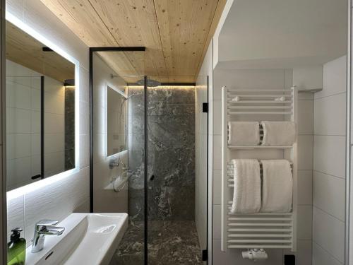 a bathroom with a shower and a sink and a mirror at Dorferwirt in Bramberg am Wildkogel