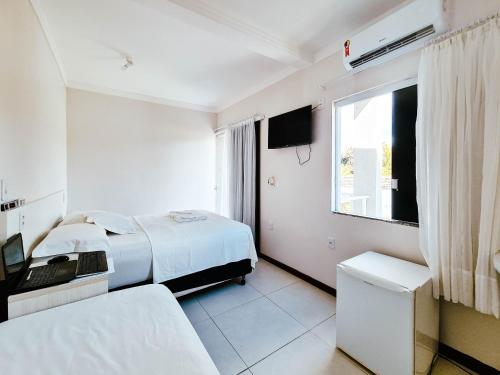 a white bedroom with a bed and a window at Pousada Praia do Flamengo Suítes in Salvador