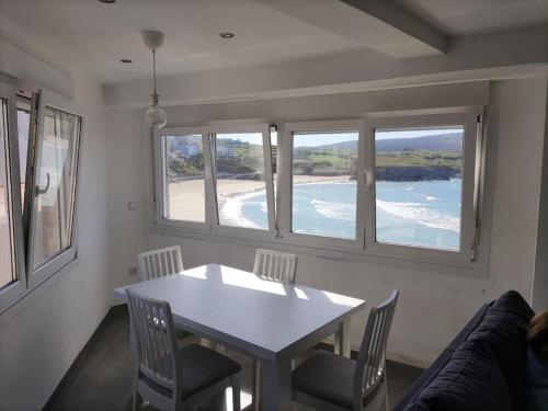 a dining room with a table and chairs and windows at Casa Consuelo Malpica in Malpica