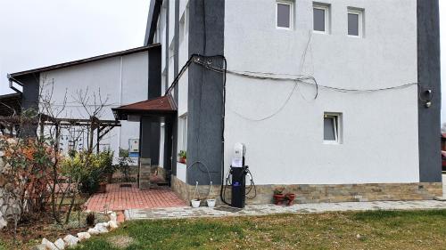 een wit huis met een gebouw met een tuin bij Pensiune Perla in Susenii Bîrgăului