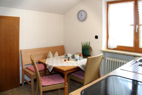 a dining room table with chairs and a clock on the wall at Gästehaus Rappenkopf in Oberstdorf