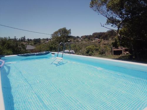 a blue swimming pool with a chair in it at Horneritos - Cabaña en Villa Serrana in Villa Serrana